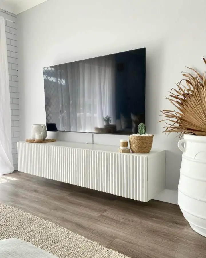 White fluted front floating media cabinet with natural decor in bright living room from @the_coastalflat showcasing ikea media center hacks & ideas.