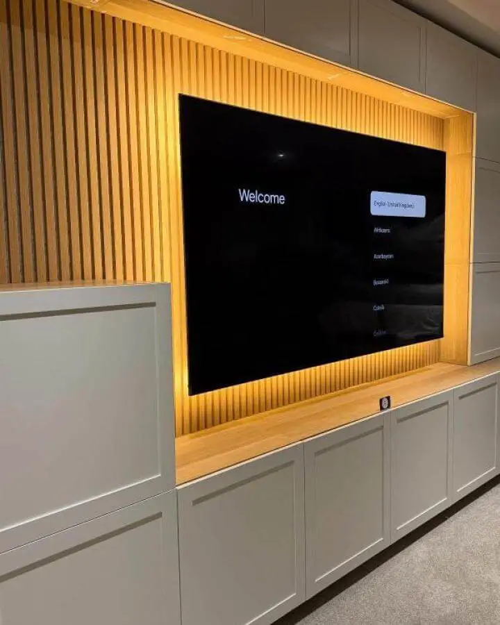Light wood slat wall with warm LED backlighting in white Ikea media center from @theflatpackmanni. Subtle, cozy modern style ikea media center hacks & ideas.