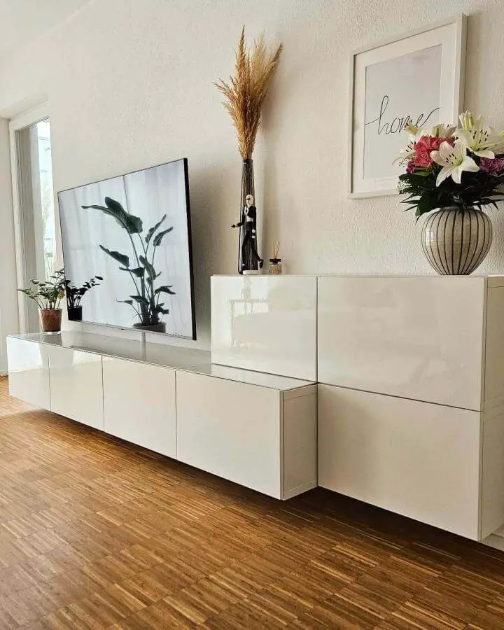 Glossy white floating media center with plants and art from @diy_home_living reflecting light in a modern living room ikea media center hacks & ideas