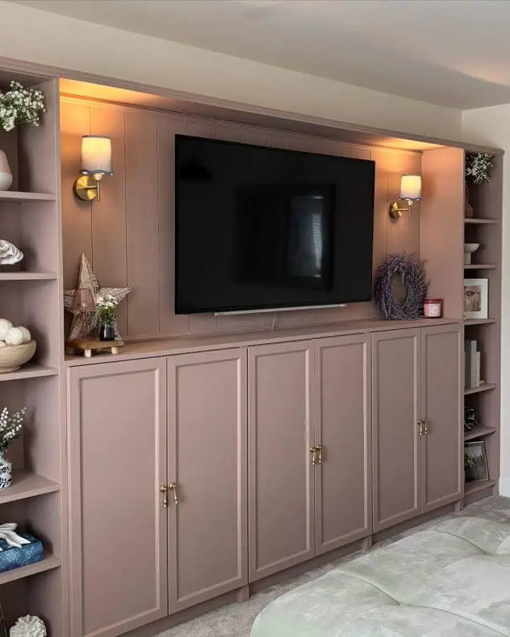 Soft blush painted media center with brass knobs and warm lighting from @lifewithbecx showing ikea media center hacks & ideas.