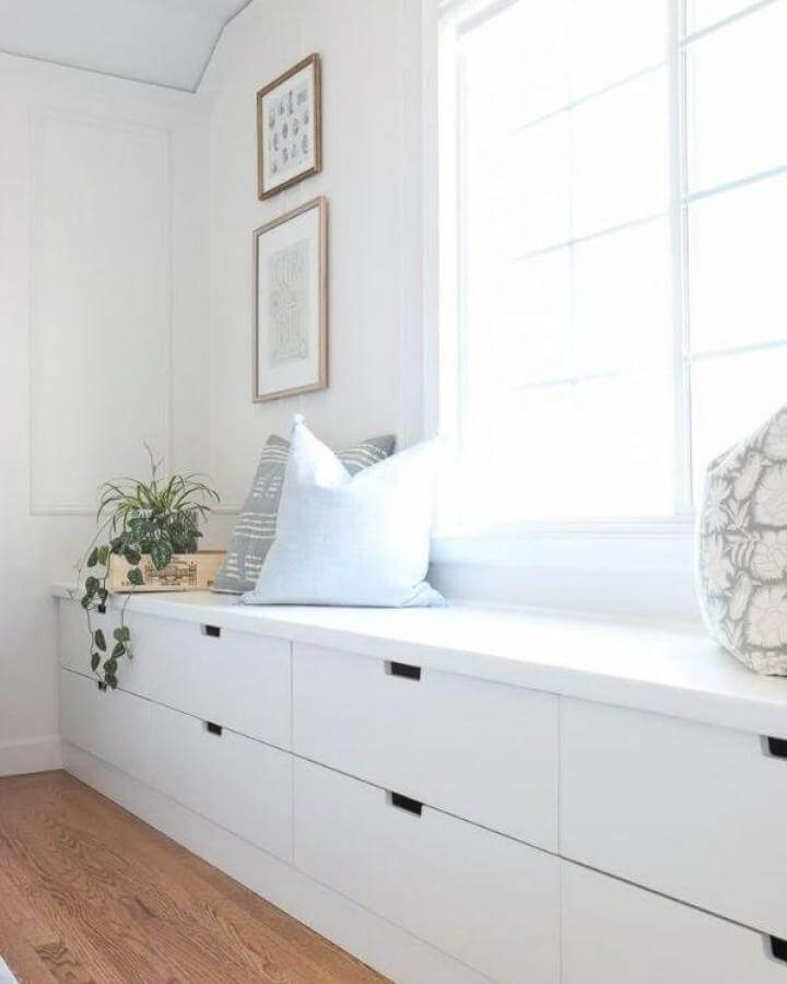 White minimalist storage bench with gray and white cushions and trailing plant from Hydrangea Treehouse ikea nordli hacks.