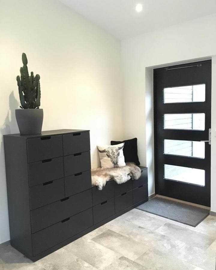 Black modular Ikea Nordli drawer units styled as entryway bench with cushions and fur throw from @parkhojden. Minimalist Scandinavian storage seating idea.