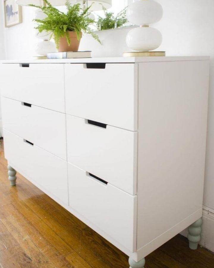 White dresser with pastel green painted wooden legs from Thou Swell. Simple ikea nordli hacks enhance vintage vibes and add elegance.