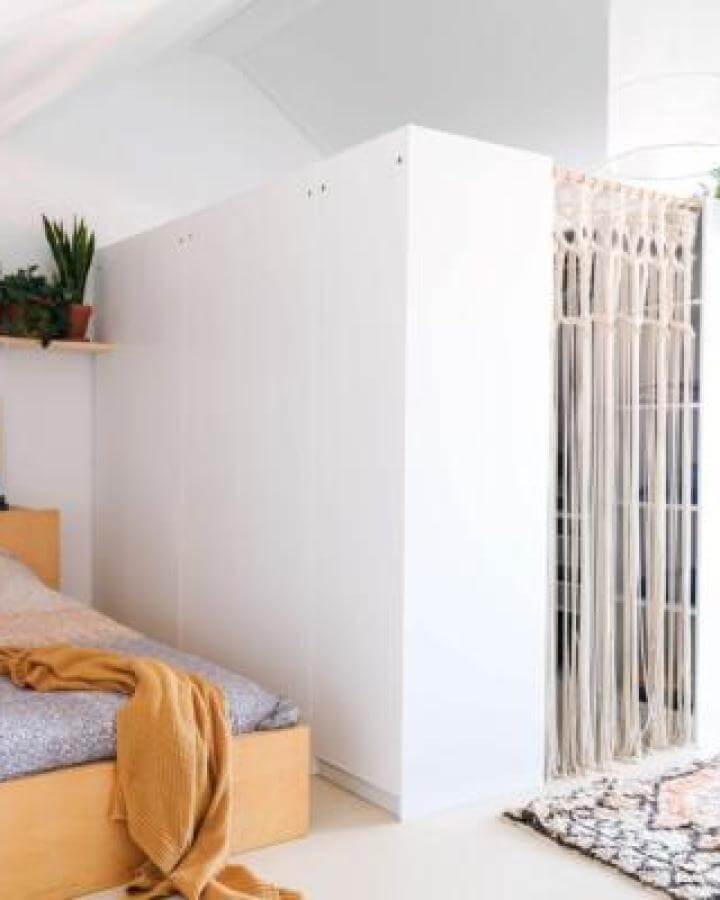 White Ikea Pax closet with handmade macrame curtain from Een Goed Verhaal soft natural fibers separate bedroom space stylishly.