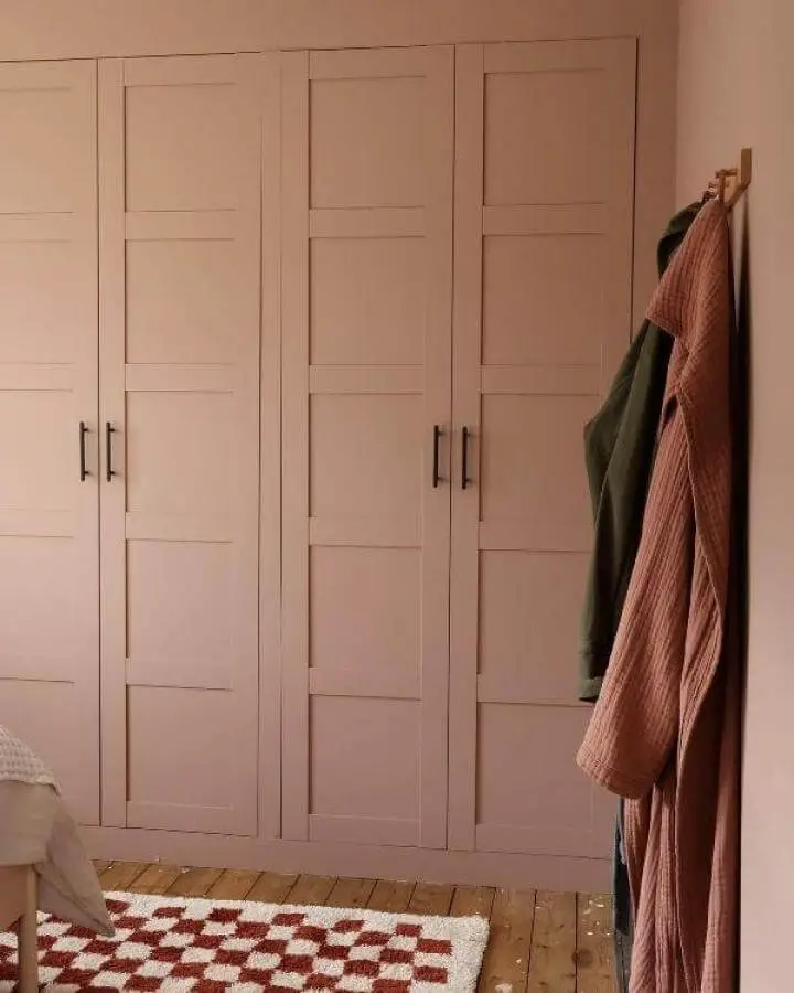 Blush pink paneled Ikea Pax wardrobe in bedroom from @weewardieterrace with black handles and warm wooden floor.