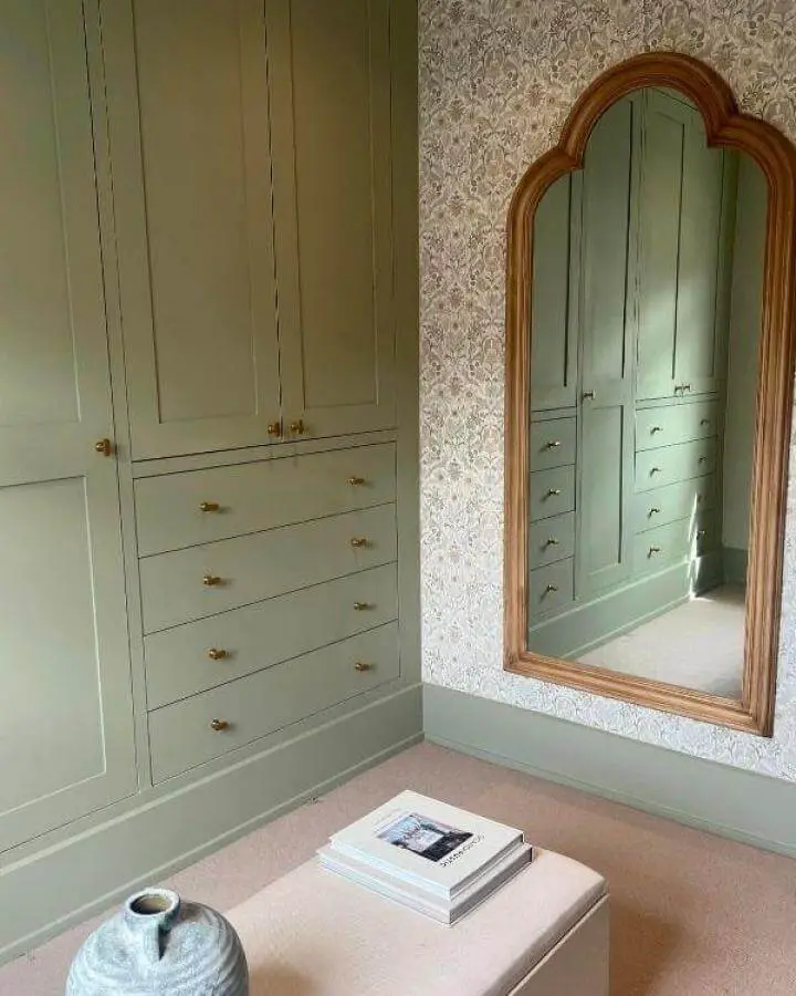 Olive green painted Ikea Pax wardrobe with brass handles and drawers from @casalawson reflecting in an ornate wooden framed mirror.