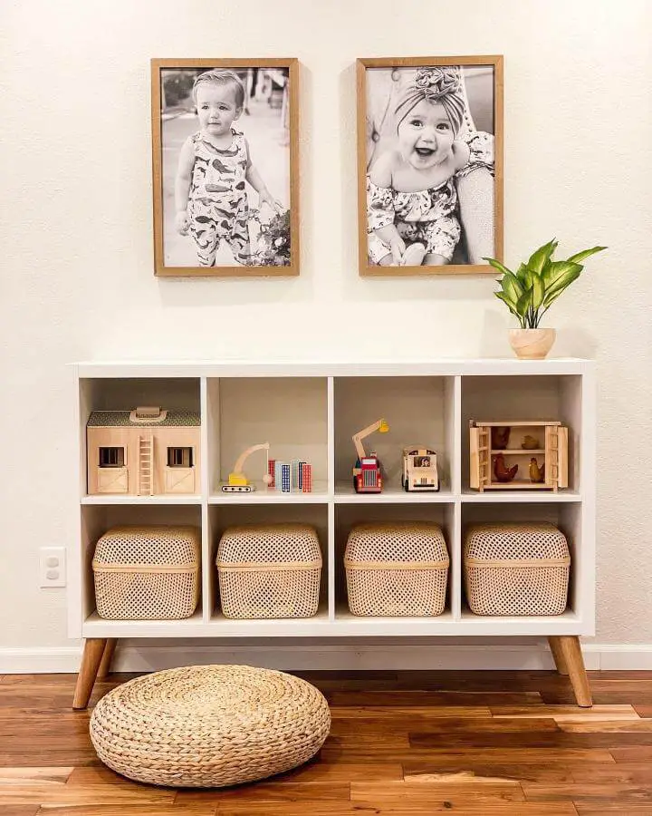Natural rattan baskets and white cube storage unit with wooden legs in a playroom from @brittanyhuffmon. Organized wooden toys and a small plant enhance ikea playroom storage hacks & ideas.
