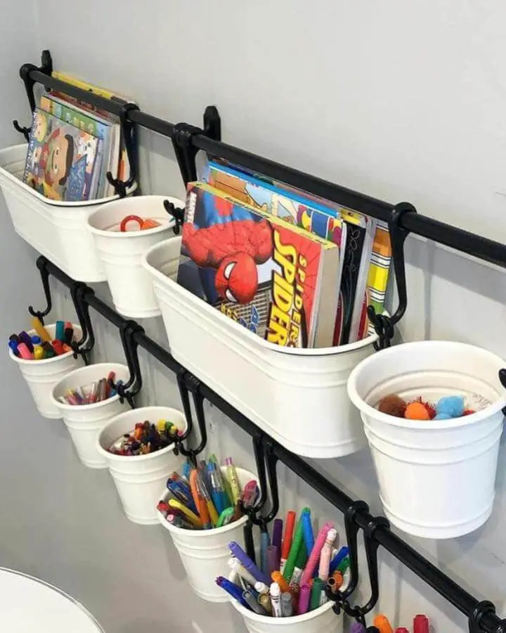 White hanging buckets and black metal rods storing books and art supplies in a playroom from @organizedandsimplified4u practical ikea playroom storage hacks & ideas
