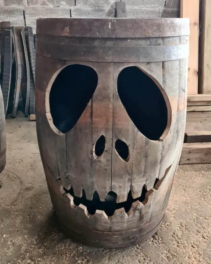 Weathered wooden barrel craft from @albabarrelcreations. Features carved skeletal face with black eye holes and stitched smile.