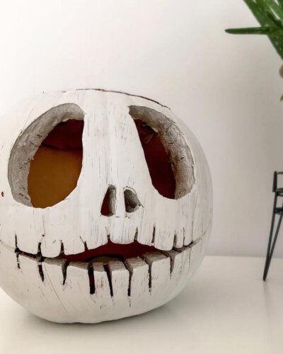 White carved pumpkin decoration from @_kirst_11. Features skeletal face design with red interior glow.