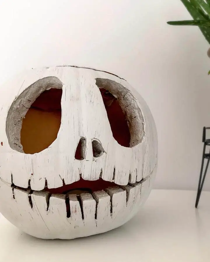 White carved pumpkin decoration from @_kirst_11. Features skeletal face design with red interior glow.