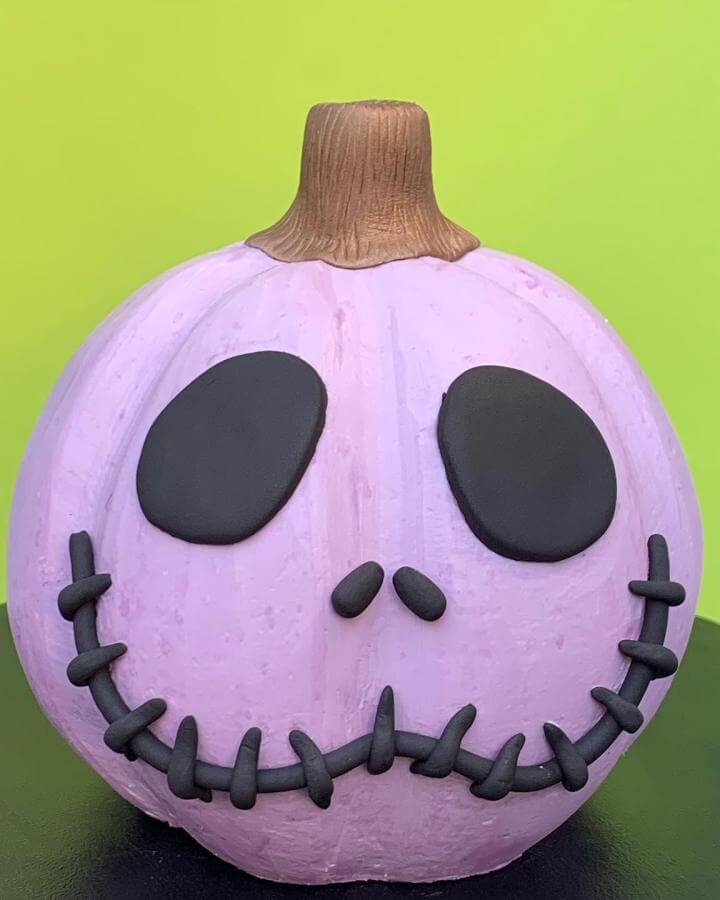 Colorful polymer clay jack skellington pumpkin from @givansweets. Purple base with black facial features and brown stem.