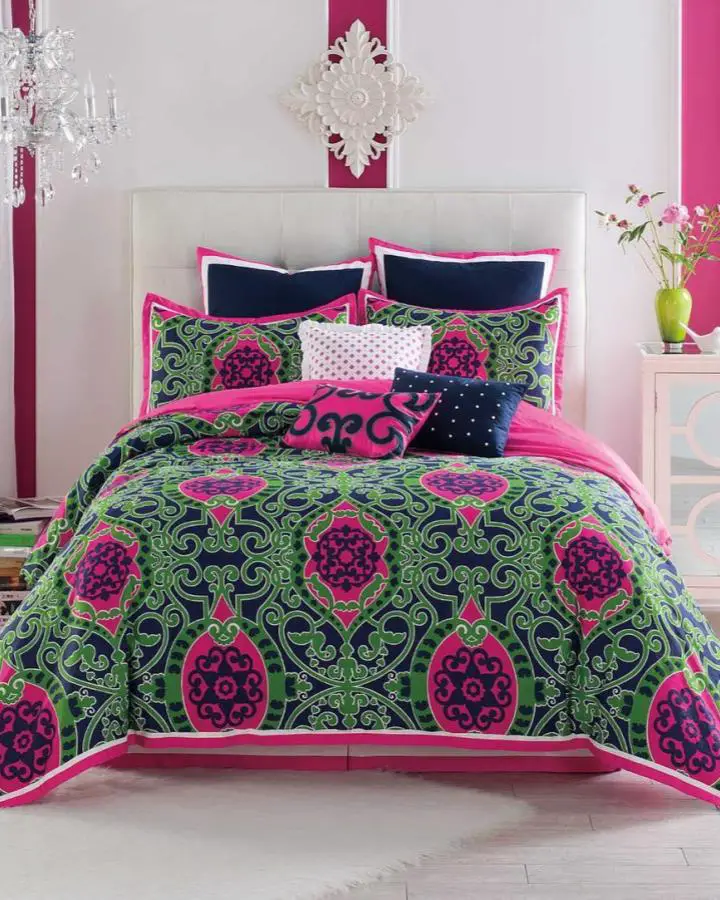 Vibrant emerald and magenta medallion bedding from @insideroom with navy accents and crystal chandelier.