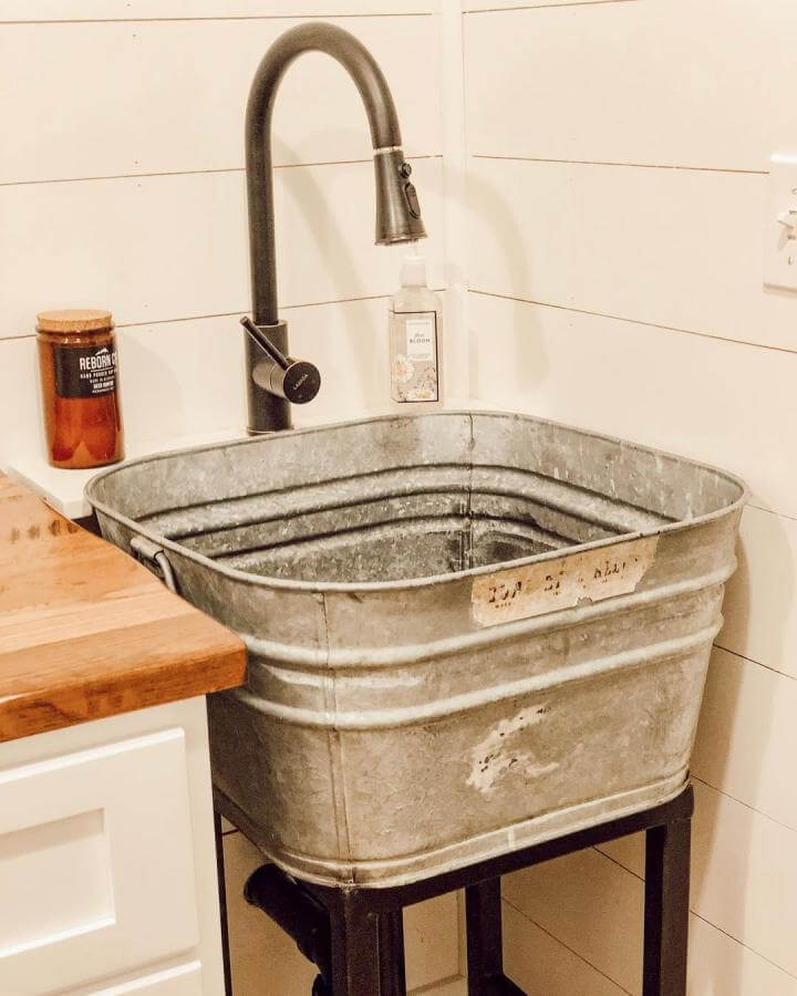 Galvanized metal tub laundry room sink ideas with black industrial faucet by @lifeonthecountyline. Rustic and functional laundry decor element.