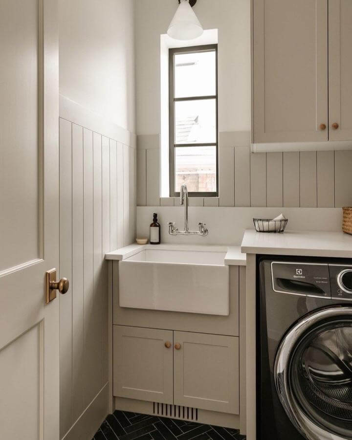 Classic white ceramic farmhouse sink with taupe cabinetry in a cozy laundry room by @lt_homes showcasing charming laundry room sink ideas.