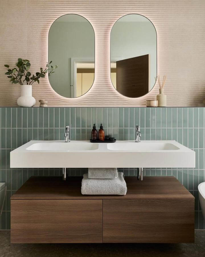 Light blue vertical tiles with floating white sink and wood cabinetry in bathroom from @cphartbathrooms creating warm, fresh decor.