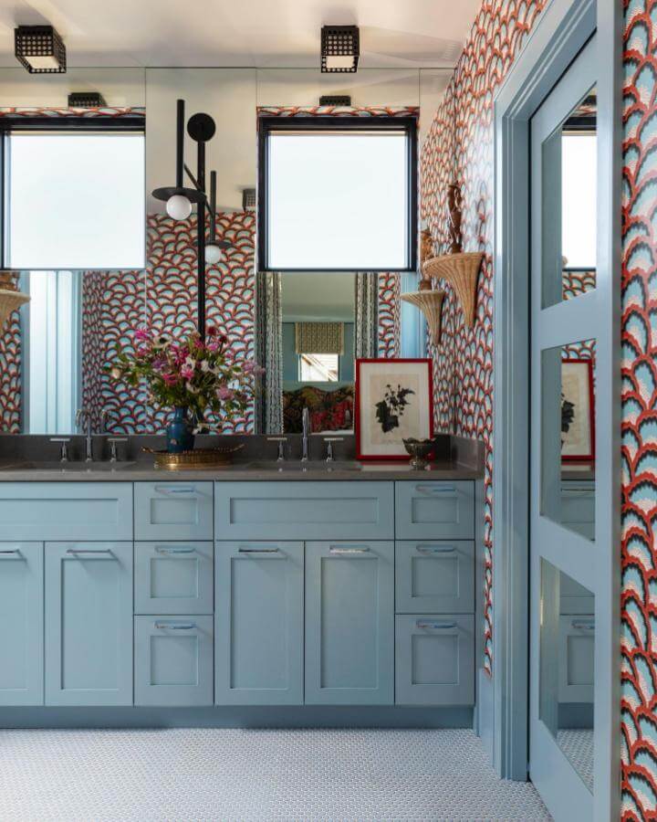 Light blue bathroom ideas with shaker style cabinets from @juliesoefer featuring contrasting wallpaper and mosaic tile floor.