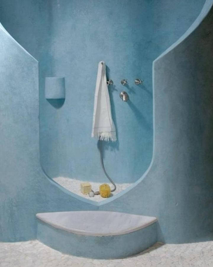 Light blue bathroom ideas with sculptural curved walls and pebble textured floor from @chiaracalvidorizza creating calm modern retreat.