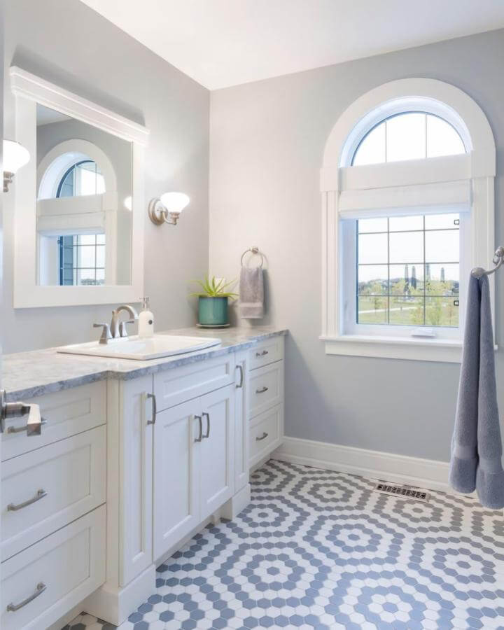Light blue bathroom ideas with hex tile flooring and white cabinetry by @hearthhomesbuilder. Bright, fresh, and stylish design.