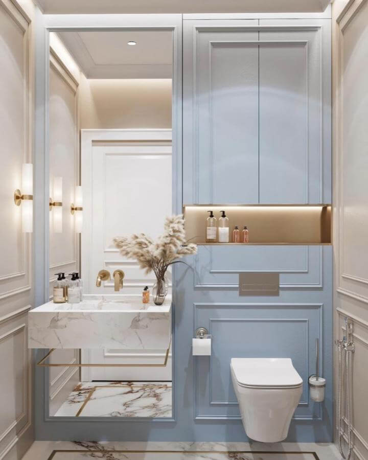 light blue bathroom ideas with elegant paneling and marble sink from @thechamberbyalia pale blue walls with gold accents and sleek fixtures
