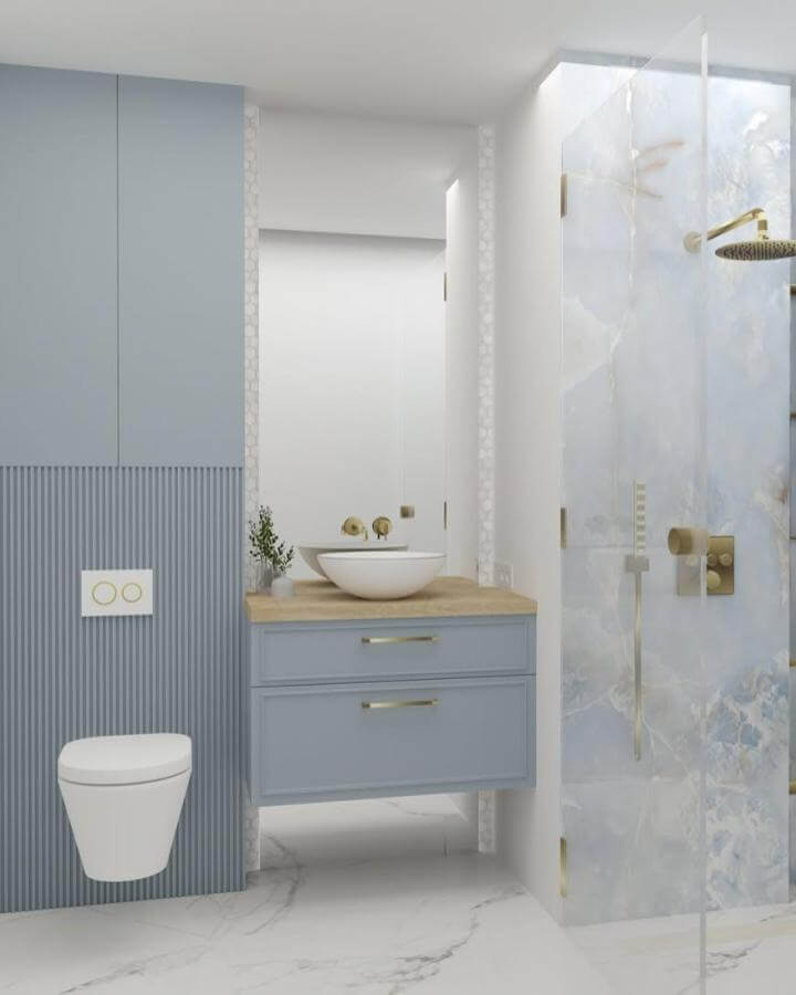 Light blue vanity with wood countertop and gold fixtures in a modern bathroom by @balance.design.nincevic showcasing light blue bathroom ideas