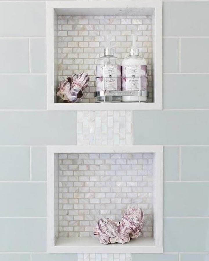 Light blue subway tile bathroom with white marble mosaic niches and coastal decor from @gogosrealestate showcasing light blue bathroom ideas.