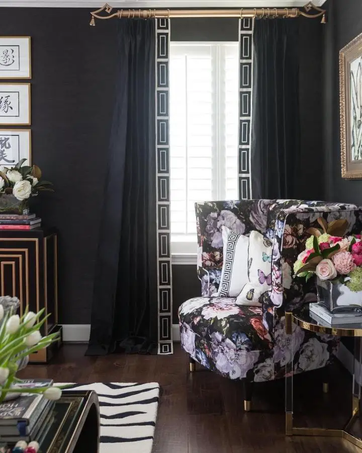 Dark floral armchair with geometric curtain trim from @casavilora_veronicasolomon. Brass rod completes the sophisticated window treatment design.