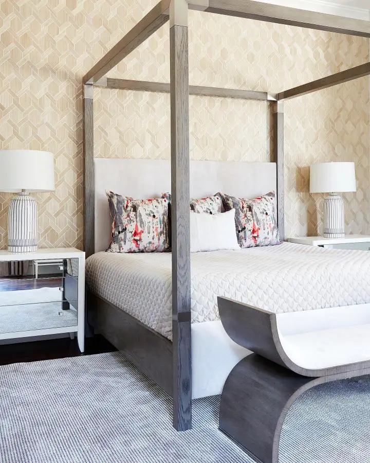 Contemporary four-poster bed with geometric cream wallpaper from @jenniferwelchdesigns. Clean lines and patterned walls create sophisticated bedroom design.