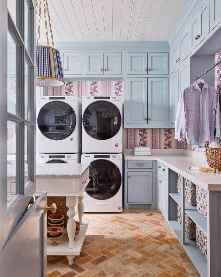 Soft blue cabinetry and floral wallpaper luxury laundry room ideas with terracotta tiles and brass accents from @torirubinsoninteriors. Bright and elegant space.