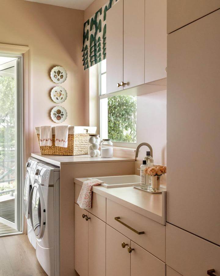 Soft warm neutral laundry room with brass hardware and patterned shade from @shani_core_interiors_ showcasing luxury laundry room ideas in a bright space.