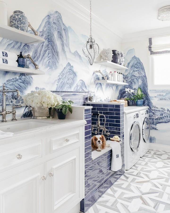 Glossy deep blue tile, scenic mountain mural laundry room from @christopherstark with porcelain accents and vintage faucets. luxury laundry room ideas.