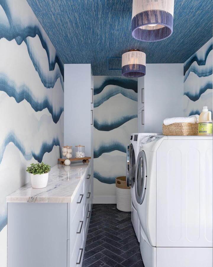 Blue ombre wallpaper and marble countertop in a luxury laundry room by @kimberleyharrisoninteriors with sleek appliances and chic lighting.