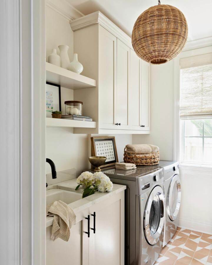Creamy white cabinetry and terracotta geometric tiled laundry room from @nativehousephotography with woven baskets and natural light luxury laundry room ideas.