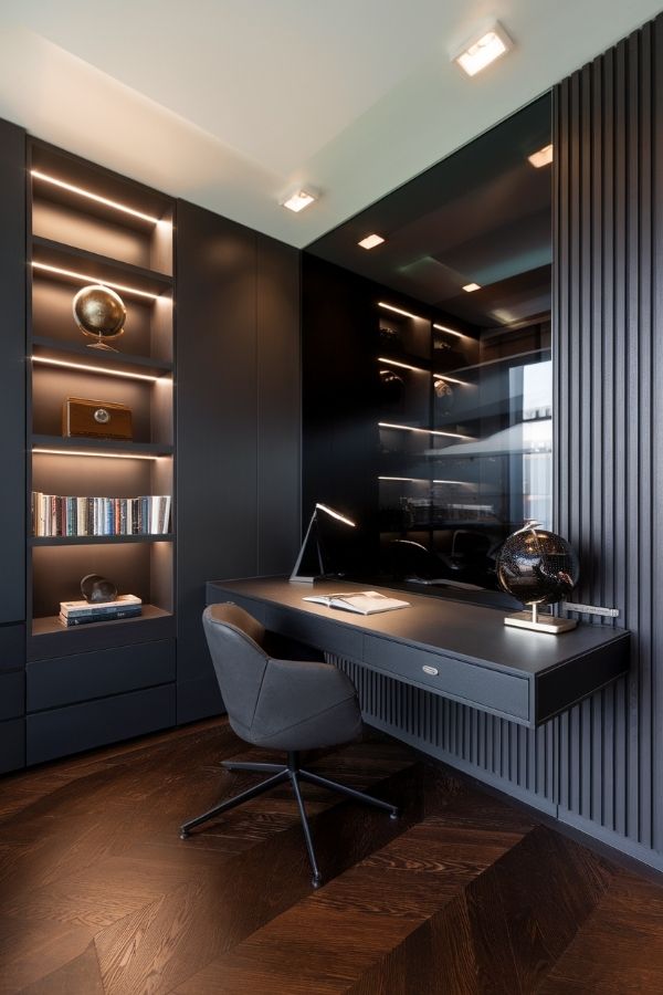 Masculine home office with dark wood desk and leather chair.