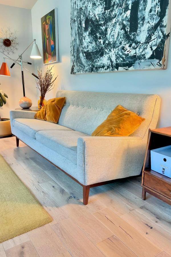 Abstract geometric print complements dark teal sofa from Swoon, enhancing mid-century modern aesthetic in a living room.