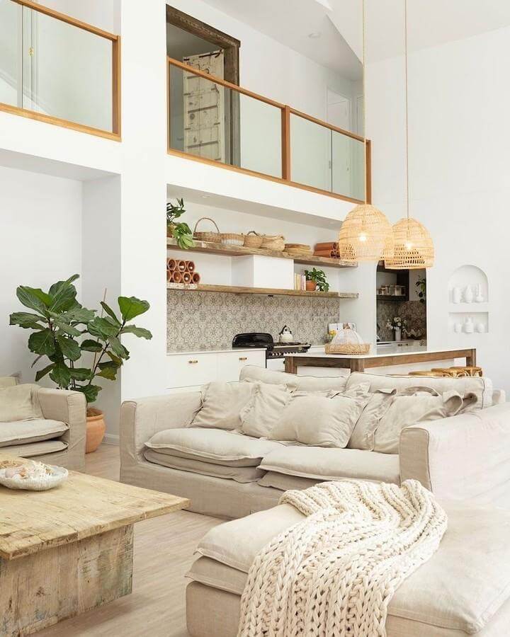 Cream linen sofas with chunky knit throw and woven rattan pendant lights in a bright coastal living room by @purelocations with natural textures and warm wood accents