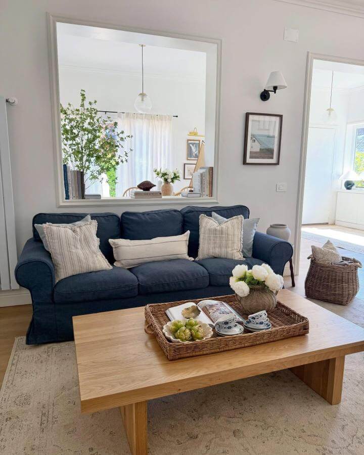 Navy blue sofa with striped pillows and natural wood coffee table from @hedonism.interior in modern coastal living room ideas with airy and fresh atmosphere.