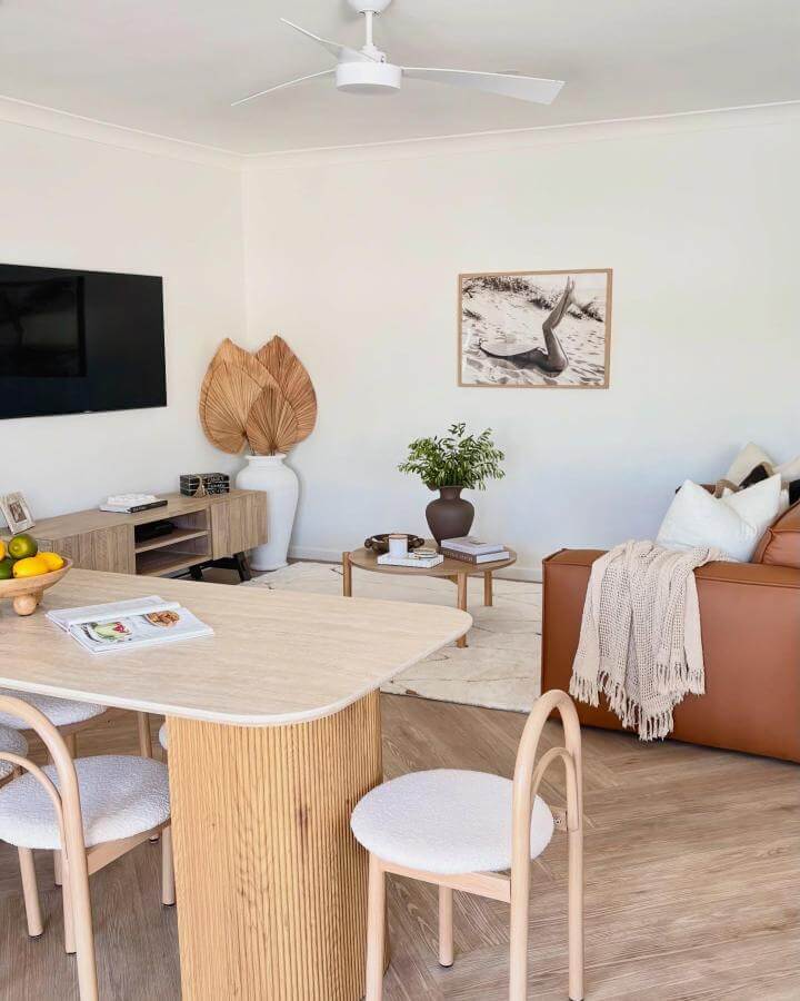 Caramel leather sofa with natural wood dining table and dried palm leaves by @saltandserenity_coastalhaven showing coastal calm and warmth.