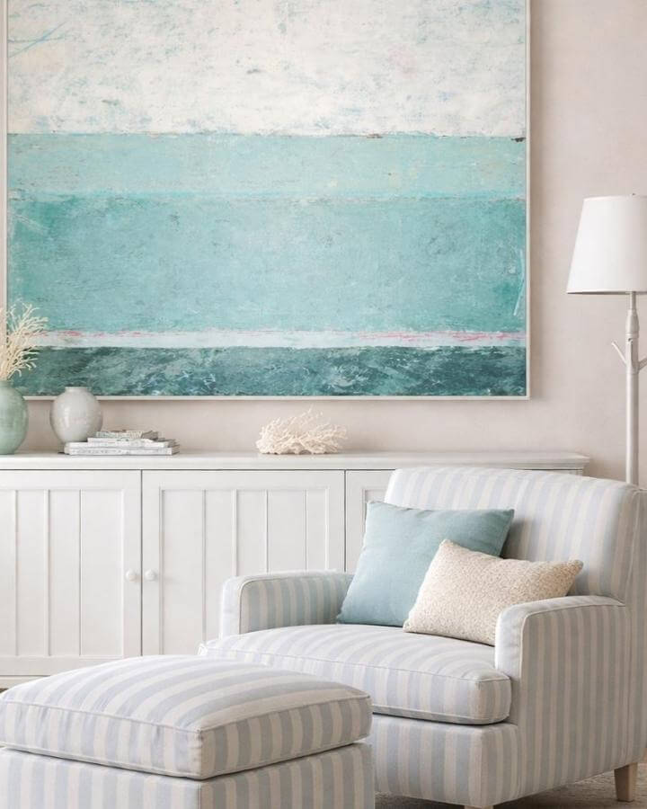Light blue striped armchair and ottoman from @michele.sammmons. Soft coastal palette with natural coral and abstract sea-inspired art.