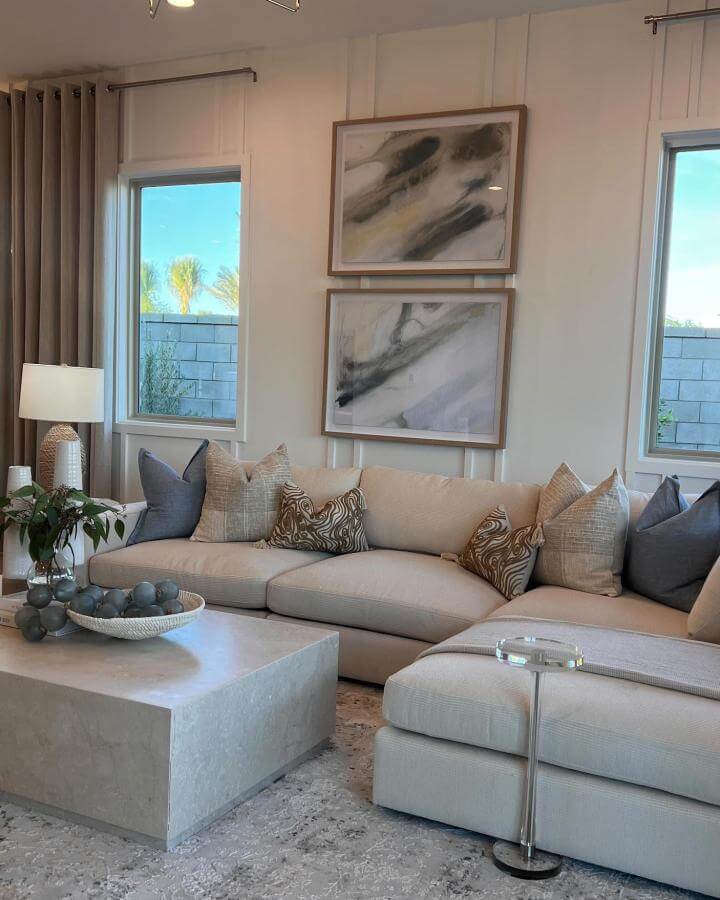 Creamy sectional sofa with blue and sand-patterned pillows in a modern coastal style living room by @cstensondesigns. Neutral and airy space with coastal inspiration.