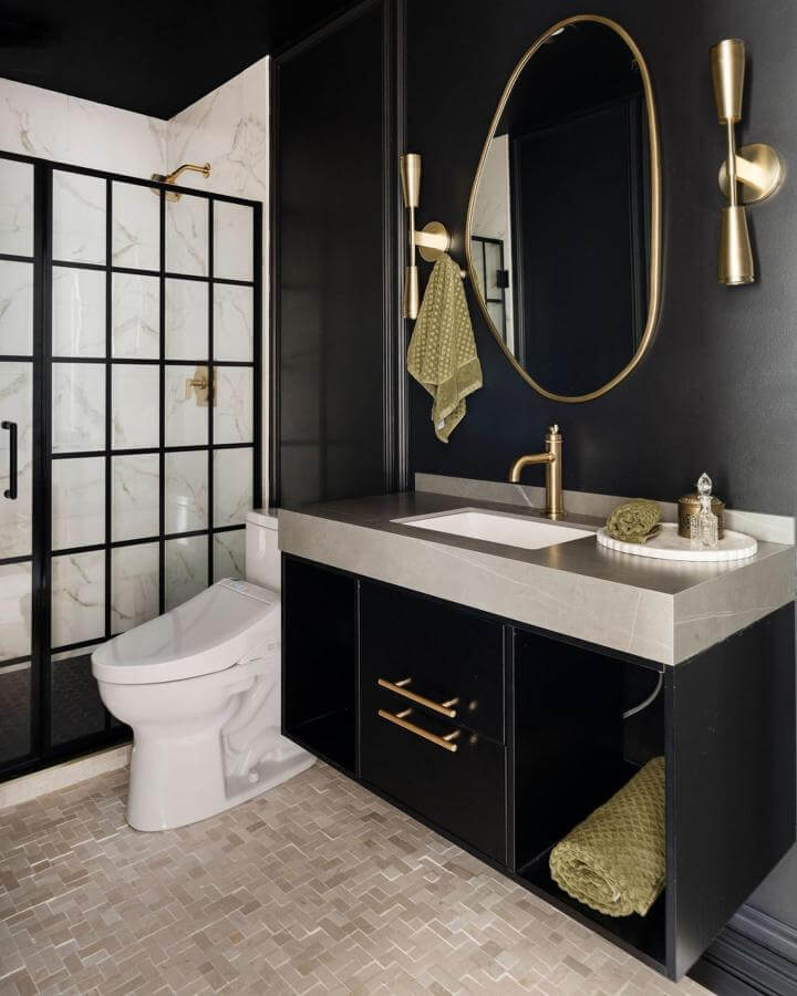 Moody black bathroom with gold fixtures and marble shower tiles by @madelineharperphoto. Sleek and warm contrast.