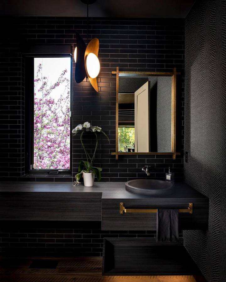 Black tiled bathroom with brass accents and matte sink from @arborsouth featuring warm moody design and textured walls.