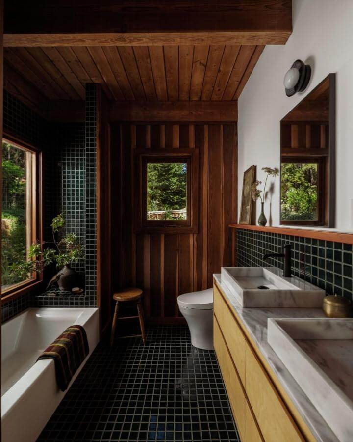 Dark green tiled bathroom floor and walls with wooden ceiling and marble sinks by @christopherstark. Cozy, natural moody style.