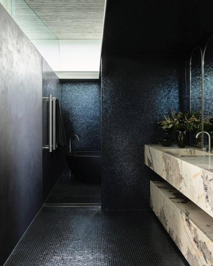 Black mosaic tiled bathroom with marble countertop and black bathtub from @smartanson showcasing sophisticated moody bathroom ideas with deep, rich textures and contrast.