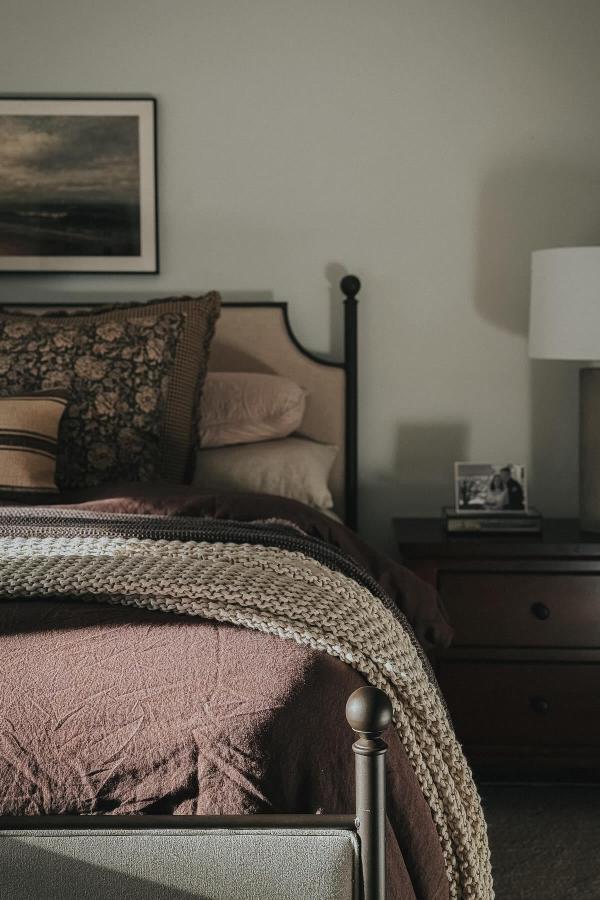 A cozy, moody bedroom with sumptuous layers for relaxing comfort.