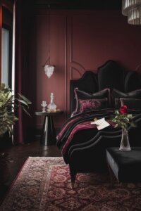 Moody romantic bedroom with soft lighting, velvet cushions, and drapes.