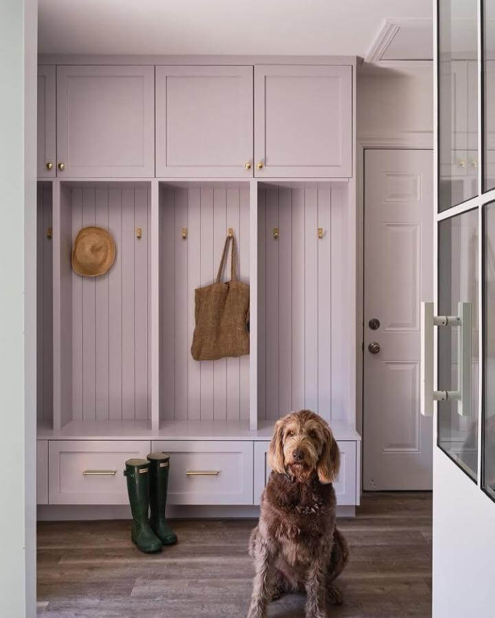 Soft lavender wooden built in cubbies with brass hooks and drawers in entryway by @anjamichalsdesign. Calm and organized space.