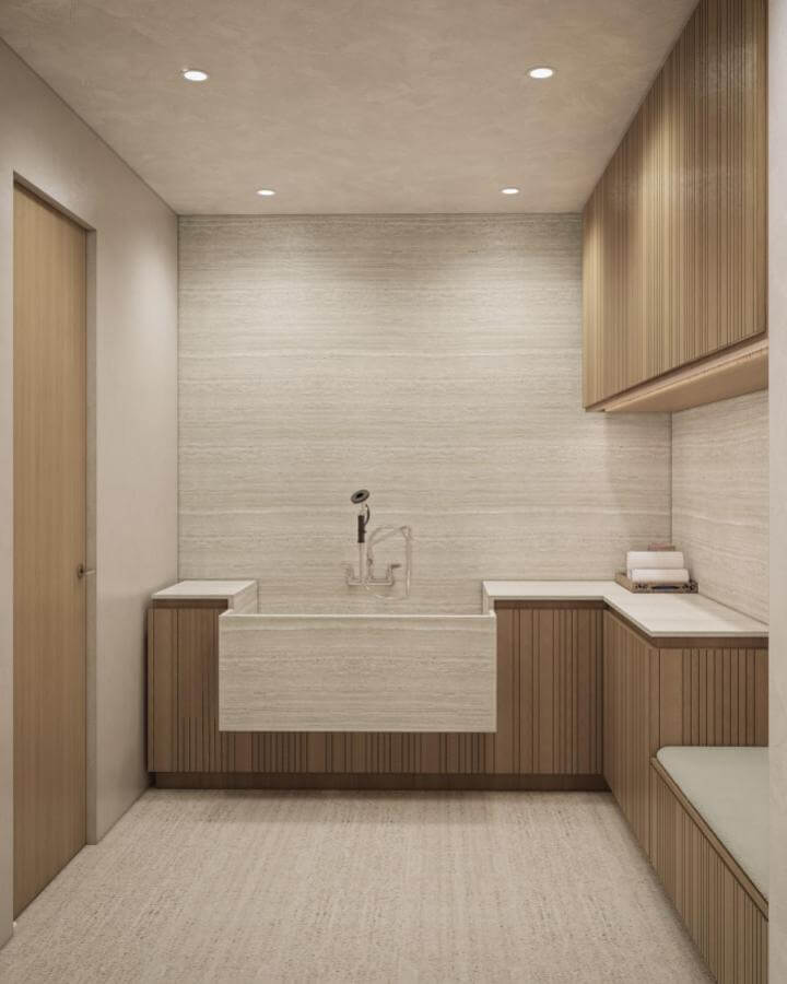 Natural wood cabinetry and stone basin dog wash area with soft beige tones from @claudiaafshardesign. Cozy mudroom pet washing setup.