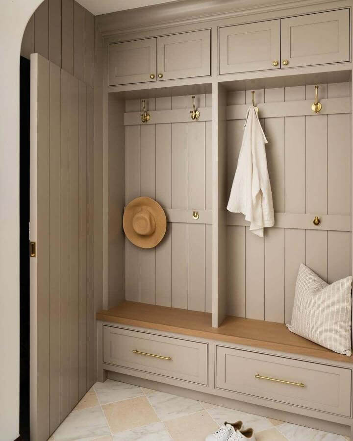 Natural stone tiled mudroom floor from @hugo.landa.garcia paired with soft beige cabinetry and brass hooks.