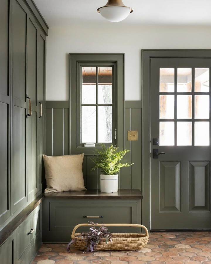 Terracotta hexagon tile flooring in an olive green wainscoted mudroom entryway from @spacecrafting_photography with natural woven basket and plant.